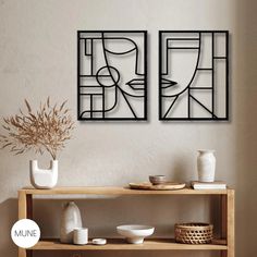 Minimalist room with abstract face wall art, wooden shelves, ceramics, and dried plants.