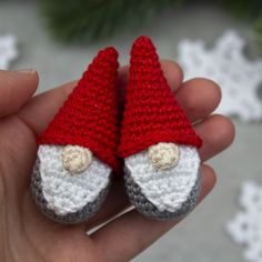 a hand holding two crocheted gnome slippers