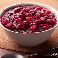 a white bowl filled with cranberry sauce next to a spoon on top of a table