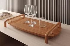 three wine glasses are sitting on a wooden tray