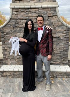 a pregnant woman standing next to a man in a tuxedo