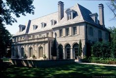 a large house with many windows and lots of greenery on the front lawn area