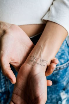 a person with a tattoo on their arm holding onto another persons hand while they both hold hands together