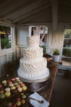 a large white wedding cake sitting on top of a table next to cupcakes