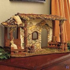 a miniature house made out of wood and stone on top of a table next to a window