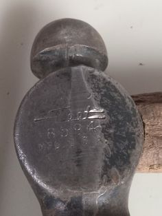 an old metal object sitting on top of a wooden pole next to a white wall