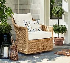 a wicker chair sitting on top of a patio next to a potted plant