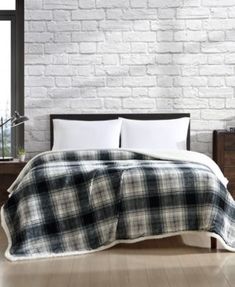 a bed with a black and white plaid comforter on top of it next to a window