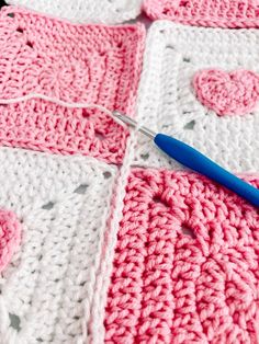 a crocheted blanket is being worked on with a blue handled knitting needle in the center