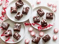 three white plates topped with brownies covered in candy canes and marshmallows