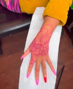 a woman's hand with pink and red designs on it sitting on top of a towel