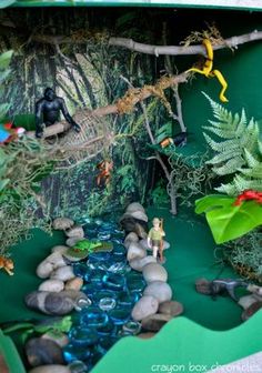 a box filled with plants and rocks in the shape of a jungle scene on display