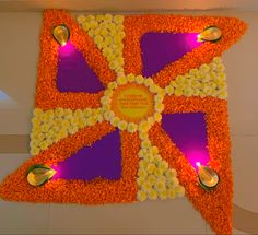 an orange and purple flowered design on the floor with candles in front of it