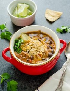 two bowls of chili and tortilla soup with limes, cilantro, and chips