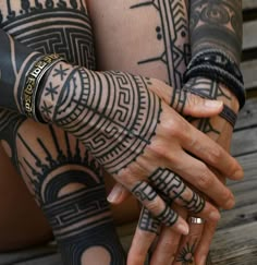 two people with tattoos on their arms holding each other's hands, both wearing rings and bracelets