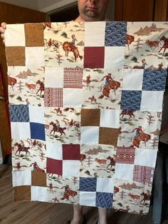 a man holding up a quilt with horses on it