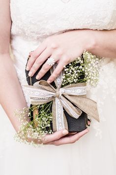 a woman in a wedding dress holding a black purse with flowers on the front and side