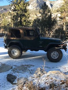 a green jeep is parked in the snow