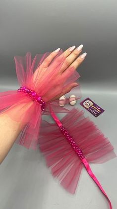 a hand holding a pink and red feathered wand