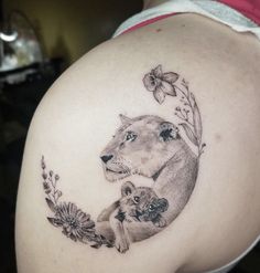 a woman with a lion tattoo on her shoulder holding a small cub in it's lap