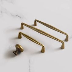 three brass handles and two knobs on a marble surface