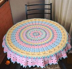 a crocheted round tablecloth on top of a chair in front of a window