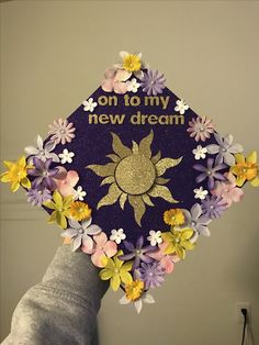 a purple and yellow graduation cap with flowers on it that says, on to my new dream