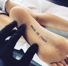 a person with black gloves on their feet has a foot tattoo that reads, may not be born