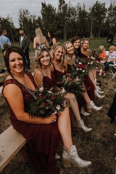 a group of women sitting next to each other on top of a wooden bench holding flowers