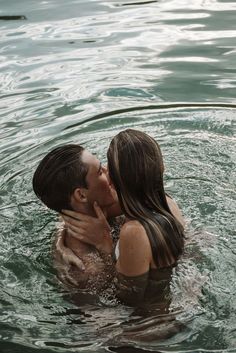 a man and woman are kissing in the water