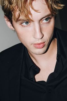 a close up of a person wearing a black shirt and looking at the camera with a serious look on his face