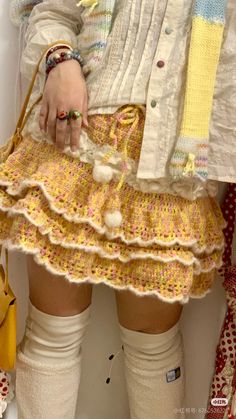 a woman is holding a purse and wearing knee - high socks with pom poms on them