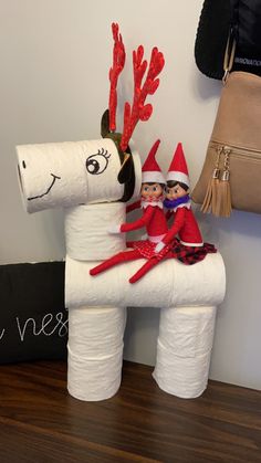 two elfs sitting on top of a white horse made out of toilet paper rolls