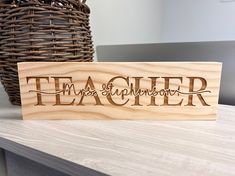 a wooden sign with the word teacher on it sitting next to a wicker basket