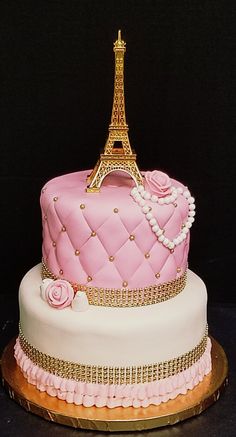 a pink cake decorated with the eiffel tower and pearls on it's sides