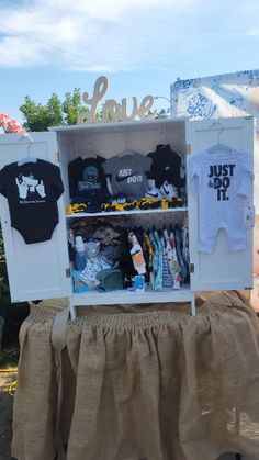 a baby's clothes and t - shirts are on display in a white cabinet