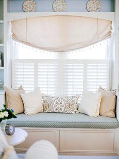 a window seat with pillows on it in front of a white bookcase and bookshelf