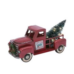 an old red truck with a christmas tree in the back