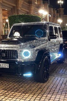 a black suv is parked in front of a building with lights on it's headlamps