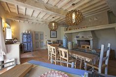 a dining room table and chairs in front of an open fire place with a chandelier hanging from the ceiling