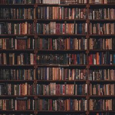 a bookshelf filled with lots of books on top of wooden shelves in a room