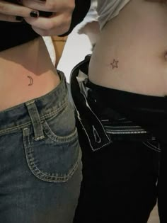 two women with small tattoos on their stomachs, one is holding a cell phone