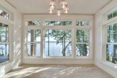 an empty room with large windows overlooking the water