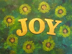 the word joy written in gold letters surrounded by sunflowers on a green background