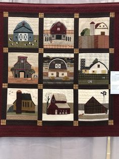 a quilted wall hanging with farm scenes and barn buildings on it's sides