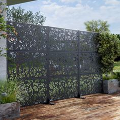 a wooden deck with an iron fence and planters on the other side, in front of a house