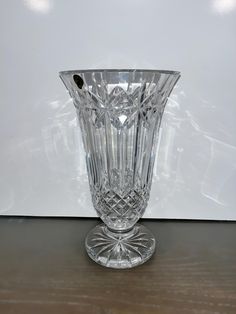 a crystal vase sitting on top of a wooden table next to a white wall and floor