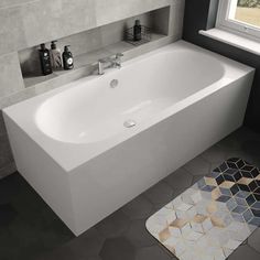 a white bathtub sitting next to a window in a bathroom with tile flooring