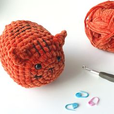 a ball of yarn and crochet hooks next to an orange cat stuffed animal