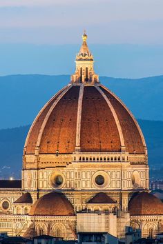 the dome of an old building with mountains in the background